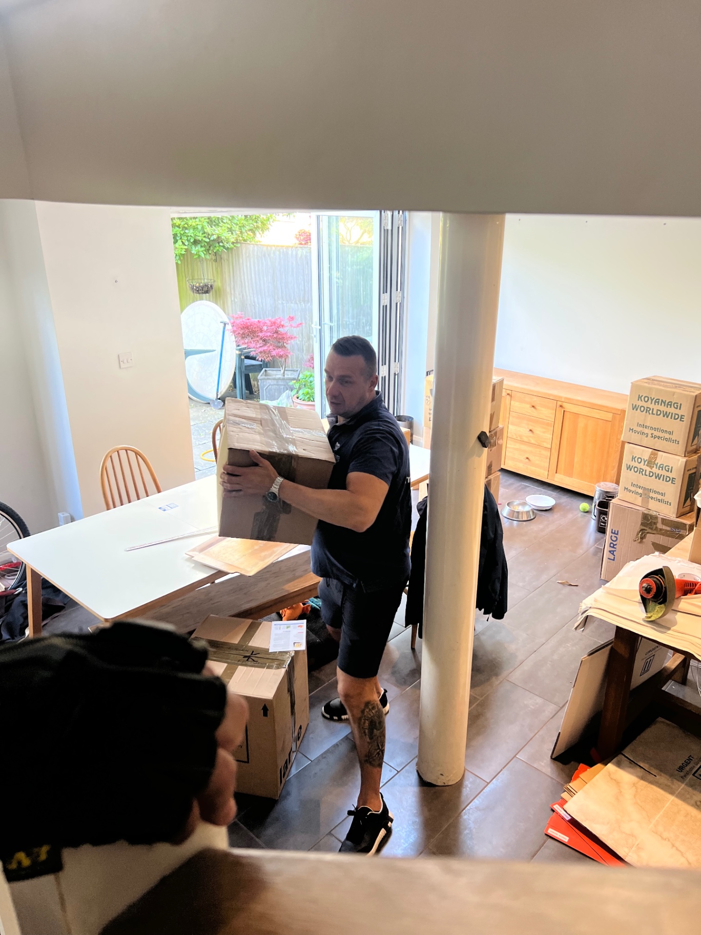 Dimond Movers team carrying a tall oak cabinet between two Bristol homes