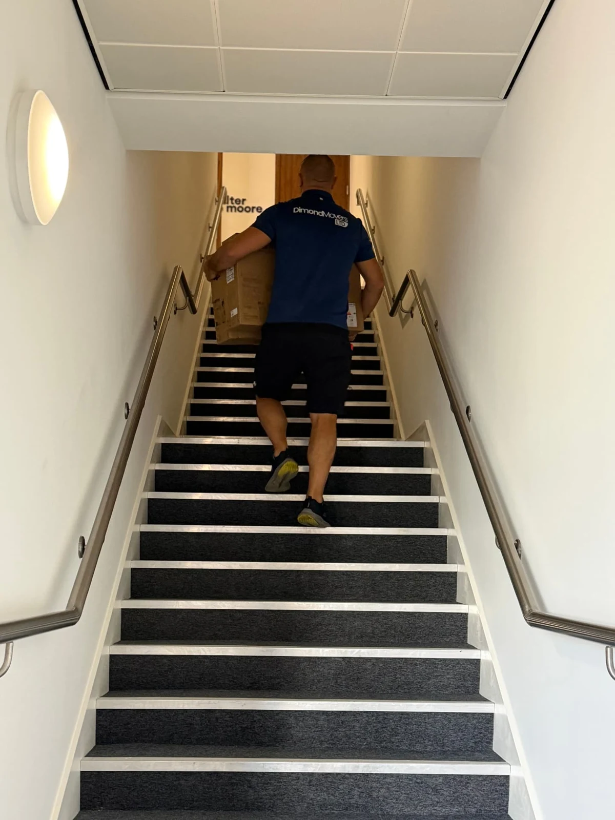 Dimond Movers team member carrying a boxed item on the office stairs