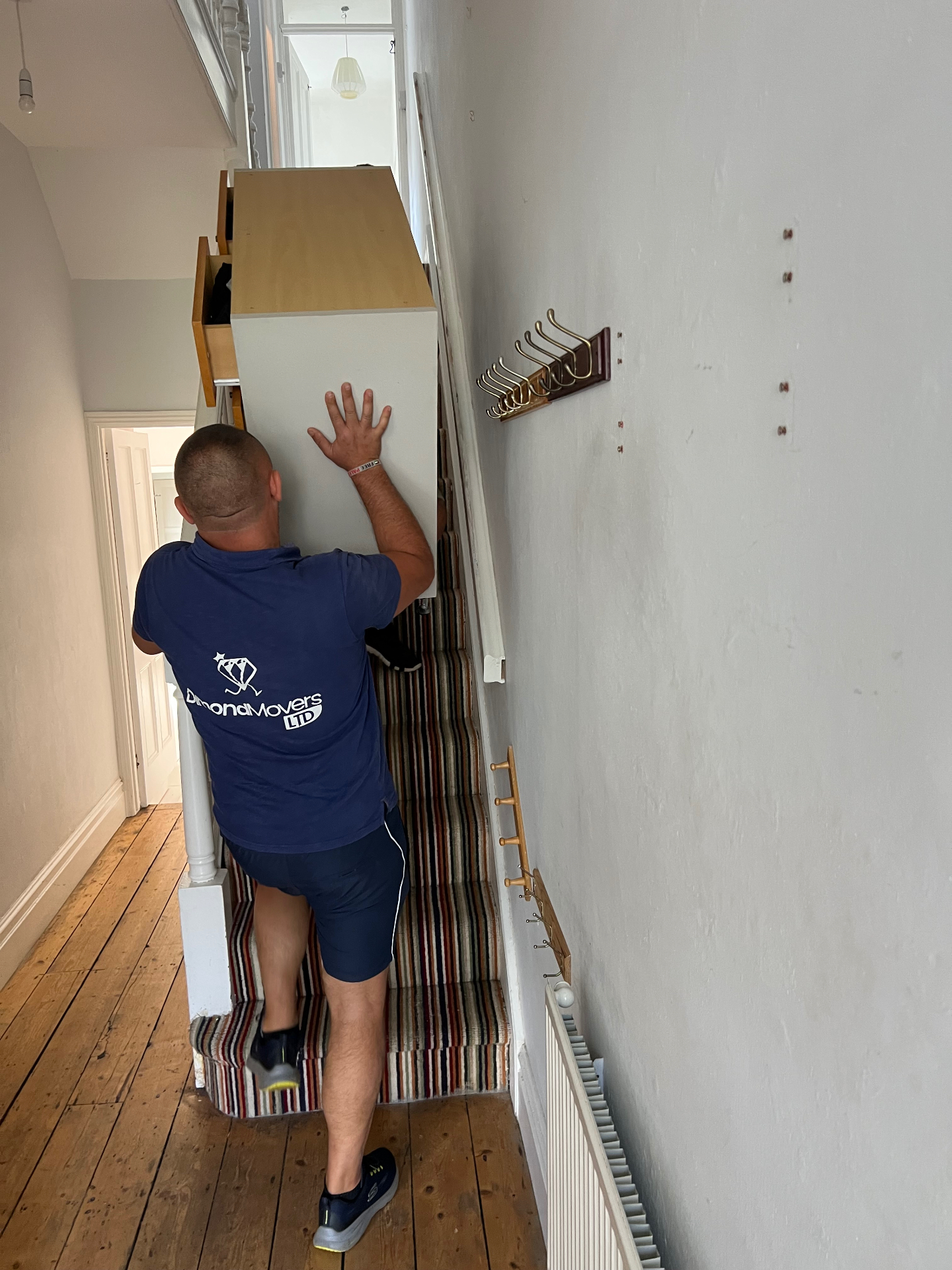 Dimond Movers carefully guiding a wardrobe down a narrow Bristol Victorian staircase