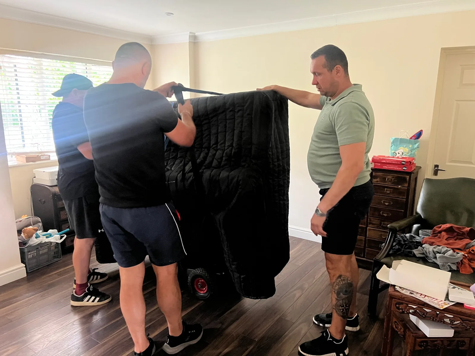 Dimond Movers movers securing an upright piano on the piano dolly with heavy-duty straps ready for transport