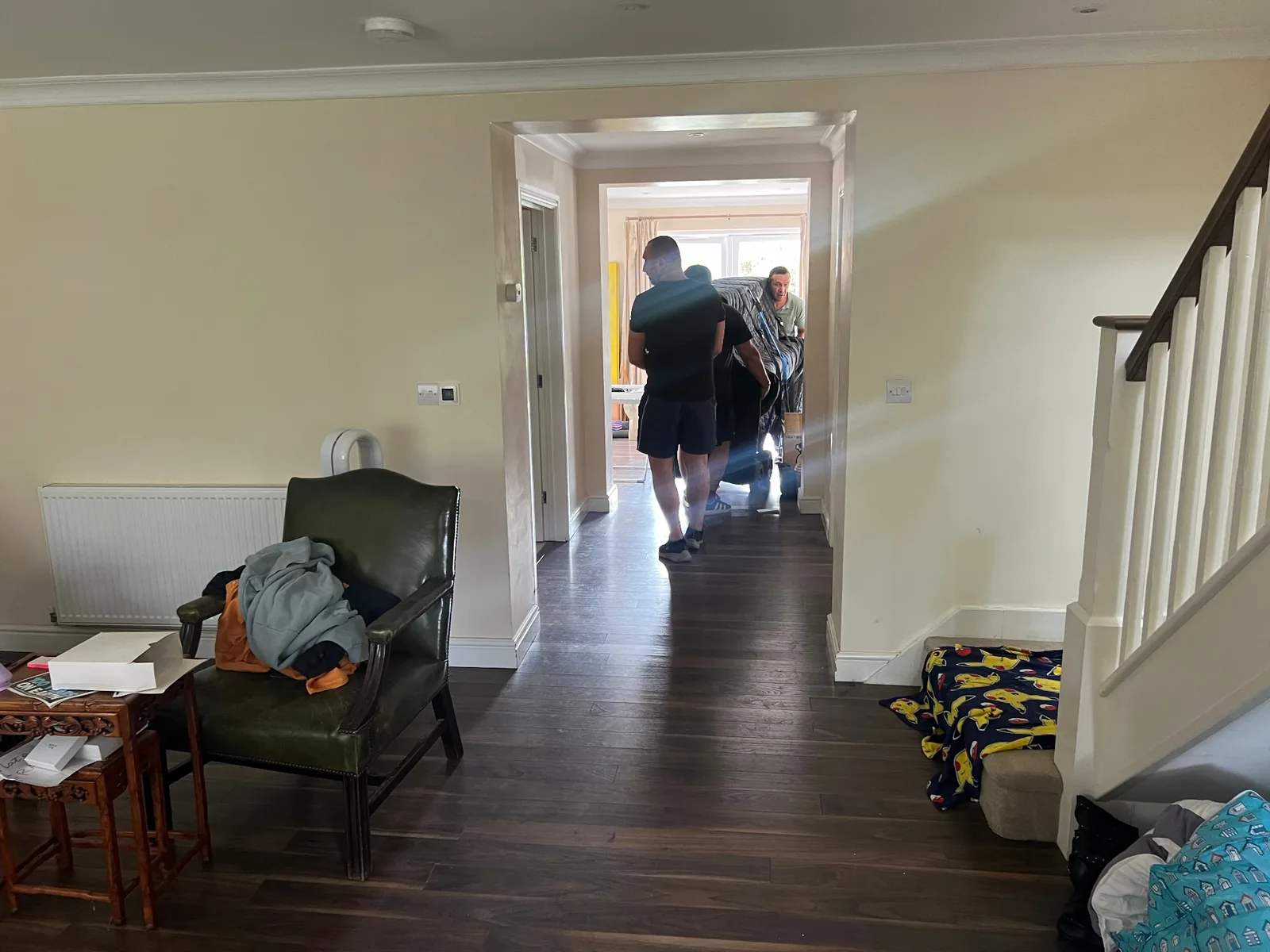 Dimond Movers crew wheeling a wrapped upright piano through a hallway and doorway on a piano dolly