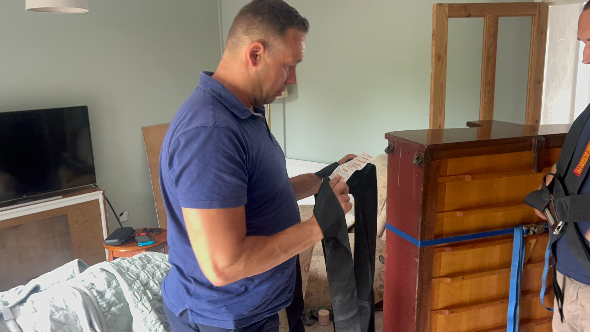Dimond Movers crew member checking the safe working load label on a piano moving strap before a move