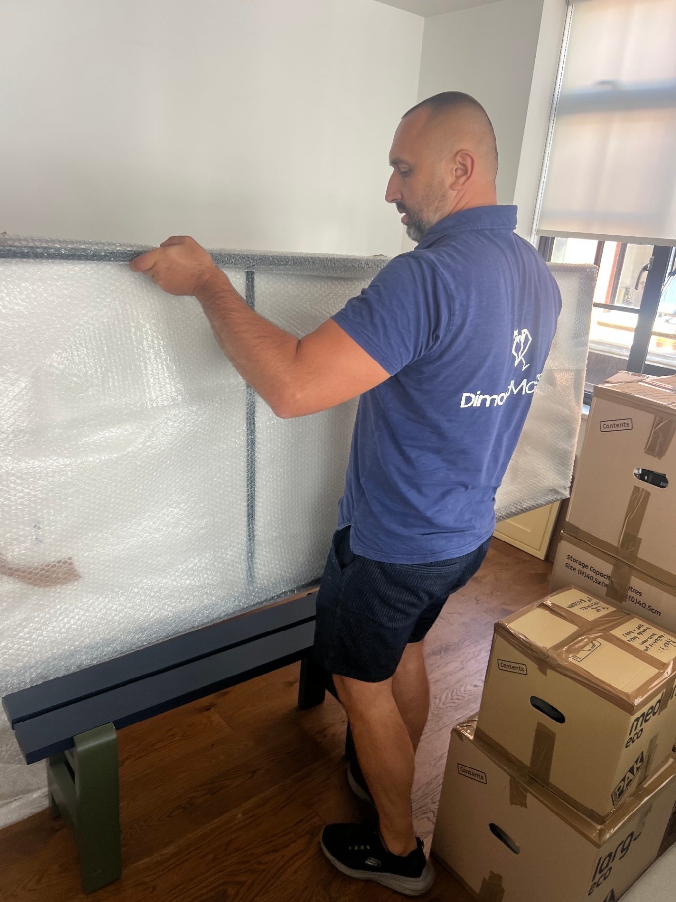 Dimond Movers packer bubble wrapping a bed frame headboard before loading
