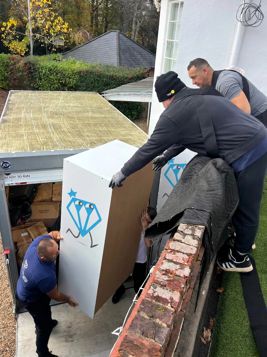 Dimond Movers team carefully loading a large wardrobe into the removals van outside a UK home